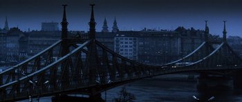 Movie still from “Spy Game” (2001), directed by Tony Scott – A view of a bridge and some buildings at night time; Extreme Wide shot, High angle