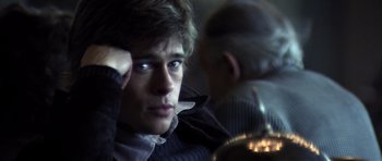 Movie still from “Spy Game” (2001), directed by Tony Scott – A young man looking at the camera while sitting in a chair; Close Up shot, Over the shoulder angle