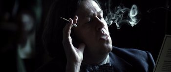 Movie still from “Spy Game” (2001), directed by Tony Scott – A man smoking a cigarette while holding a cell phone to his ear; Close Up shot, Low angle