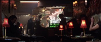 Movie still from “Spy Game” (2001), directed by Tony Scott – A group of people standing around a bar with drinks; Wide shot, Over the shoulder angle