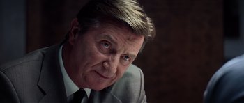 Movie still from “Spy Game” (2001), directed by Tony Scott – An older man wearing a suit and tie looking at the camera; Close Up shot, Low angle