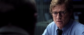 Movie still from “Spy Game” (2001), directed by Tony Scott – An older man wearing glasses and a blue shirt; Close Up shot, Over the shoulder angle