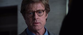 Movie still from “Spy Game” (2001), directed by Tony Scott – A person wearing glasses and a jacket; Close Up shot, Over the shoulder angle