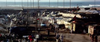 Movie still from “Spy Game” (2001), directed by Tony Scott – A group of people walking on a beach near the ocean; Extreme Wide shot, High angle
