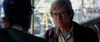 Movie still from “Spy Game” (2001), directed by Tony Scott – An older man wearing glasses and a brown jacket; Close Up shot, Over the shoulder angle
