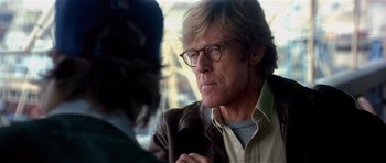Movie still from “Spy Game” (2001), directed by Tony Scott – A person wearing glasses and a leather jacket; Close Up shot, Over the shoulder angle