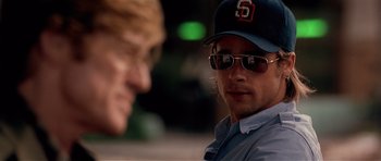 Movie still from “Spy Game” (2001), directed by Tony Scott – A man wearing a baseball cap and sunglasses talking to another man; Close Up shot, Over the shoulder angle