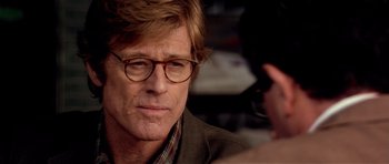 Movie still from “Spy Game” (2001), directed by Tony Scott – A person wearing glasses and a jacket; Close Up shot, Over the shoulder angle