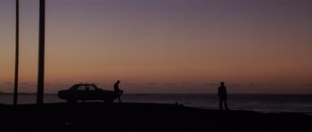 Movie still from “Spy Game” (2001), directed by Tony Scott – Two people standing on the beach at sunset; Extreme Wide shot, Low angle
