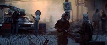 Movie still from “Spy Game” (2001), directed by Tony Scott – A man holding a gun while standing next to a barbed wire fence; Wide shot, Over the shoulder angle
