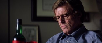 Movie still from “Spy Game” (2001), directed by Tony Scott – An older man wearing glasses looking down at a red object; Close Up shot, Low angle