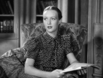 Movie still from “Stage Door” (1937), directed by Gregory La Cava – A woman sitting in a chair holding a book in her hands; Medium shot, High angle
