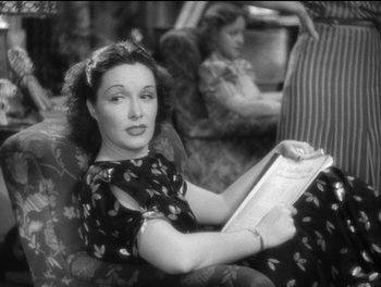 Movie still from “Stage Door” (1937), directed by Gregory La Cava – A black and white photo of a woman reading a book; Medium shot, High angle