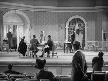 Movie still from “Stage Door” (1937), directed by Gregory La Cava – A black and white photo of people sitting around a table; Extreme Wide shot, High angle
