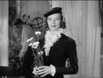 Movie still from “Stage Door” (1937), directed by Gregory La Cava – A woman holding a vase of flowers while wearing a hat; Medium shot, Low angle