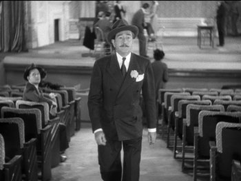 Movie still from “Stage Door” (1937), directed by Gregory La Cava – A man in a suit and hat walking through a theater; Wide shot, High angle