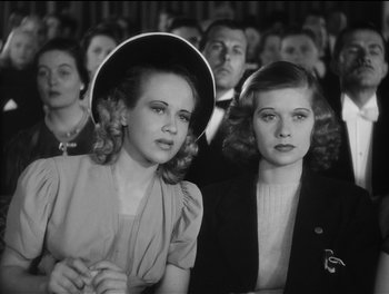 A couple of women sitting next to each other in a crowd