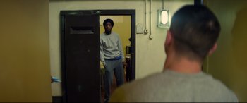 Movie still from “Starred Up” (2013), directed by David Mackenzie – A man standing in front of a mirror in a room; Medium shot, Over the shoulder angle