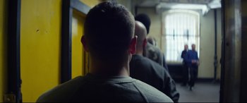 Movie still from “Starred Up” (2013), directed by David Mackenzie – A group of men standing next to each other in front of a window; Medium shot, Over the shoulder angle