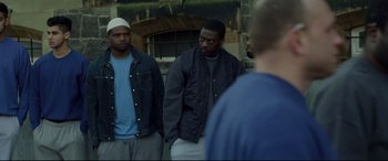 Movie still from “Starred Up” (2013), directed by David Mackenzie – A group of men standing next to each other on the street; Medium shot, Over the shoulder angle