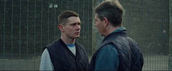 Movie still from “Starred Up” (2013), directed by David Mackenzie – Two men standing next to each other in front of a building; Medium shot, Over the shoulder angle