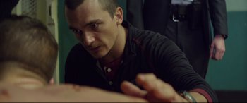 Movie still from “Starred Up” (2013), directed by David Mackenzie – A person sitting at a table; Close Up shot, Over the shoulder angle