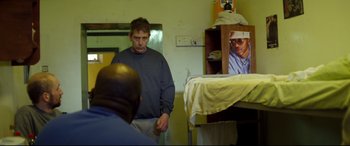 Movie still from “Starred Up” (2013), directed by David Mackenzie – A man standing in front of another man in a room; Medium shot, Over the shoulder angle