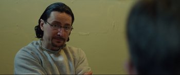 Movie still from “Starred Up” (2013), directed by David Mackenzie – A man wearing glasses and a white shirt is talking to a woman; Close Up shot, Over the shoulder angle