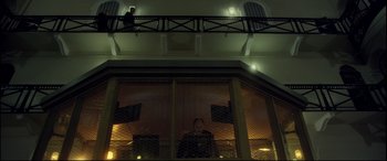 Movie still from “Starred Up” (2013), directed by David Mackenzie – A man standing in front of a window in a building; Wide shot, Low angle