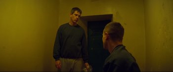 Movie still from “Starred Up” (2013), directed by David Mackenzie – A man standing next to another man in front of a door; Medium shot, Over the shoulder angle