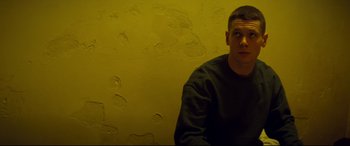 Movie still from “Starred Up” (2013), directed by David Mackenzie – A man sitting in front of a yellow wall; Close Up shot, Low angle