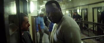 Movie still from “Starred Up” (2013), directed by David Mackenzie – A man standing in front of a group of other people; Close Up shot, Over the shoulder angle