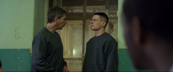 Movie still from “Starred Up” (2013), directed by David Mackenzie – Two men standing next to each other in front of a cage; Medium shot, Over the shoulder angle