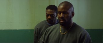 Movie still from “Starred Up” (2013), directed by David Mackenzie – Two men standing next to each other in front of a wall; Medium shot, Over the shoulder angle