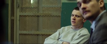 Movie still from “Starred Up” (2013), directed by David Mackenzie – A man sitting in a chair in front of a green wall; Close Up shot, Over the shoulder angle