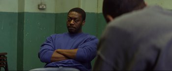 Movie still from “Starred Up” (2013), directed by David Mackenzie – A man sitting in front of another man in a room; Medium shot, Over the shoulder angle
