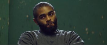 Movie still from “Starred Up” (2013), directed by David Mackenzie – A person with a beard looking to his left; Close Up shot, Over the shoulder angle