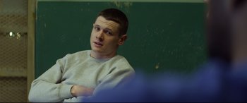 Movie still from “Starred Up” (2013), directed by David Mackenzie – A man sitting in front of a green wall; Medium shot, Over the shoulder angle