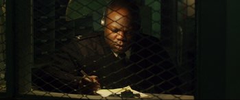 Movie still from “Starred Up” (2013), directed by David Mackenzie – A man sitting at a table writing on a piece of paper; Close Up shot, High angle