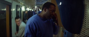 Movie still from “Starred Up” (2013), directed by David Mackenzie – A man talking on a phone while standing in a room; Close Up shot, High angle