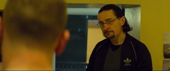 Movie still from “Starred Up” (2013), directed by David Mackenzie – A man with glasses looking at himself in a mirror; Close Up shot, Over the shoulder angle