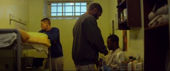 Movie still from “Starred Up” (2013), directed by David Mackenzie – A man is getting his hair cut at a barber shop; Medium shot, Over the shoulder angle