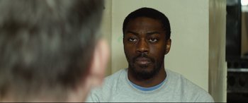Movie still from “Starred Up” (2013), directed by David Mackenzie – A man looking into a mirror while wearing a white t - shirt; Close Up shot, Over the shoulder angle
