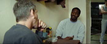 Movie still from “Starred Up” (2013), directed by David Mackenzie – Two men are sitting at a table and talking to each other; Medium shot, Over the shoulder angle