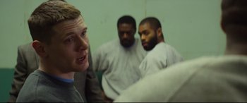 Movie still from “Starred Up” (2013), directed by David Mackenzie – Three men are in a room and one man is looking at the camera; Medium shot, Over the shoulder angle