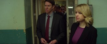 Movie still from “Starred Up” (2013), directed by David Mackenzie – A man in a suit and tie holding a cell phone; Medium shot, Over the shoulder angle