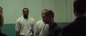 Movie still from “Starred Up” (2013), directed by David Mackenzie – A group of men standing next to each other in front of a wall; Medium shot, Over the shoulder angle