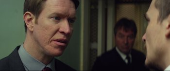 Movie still from “Starred Up” (2013), directed by David Mackenzie – A person wearing a suit and tie; Close Up shot, Over the shoulder angle