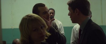 Movie still from “Starred Up” (2013), directed by David Mackenzie – A group of people standing around each other in a room; Medium shot, Over the shoulder angle