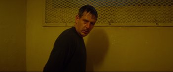 Movie still from “Starred Up” (2013), directed by David Mackenzie – A man standing in front of a yellow wall; Close Up shot, Low angle